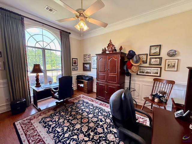 home office with wood finished floors, crown molding, ceiling fan, a wainscoted wall, and a decorative wall