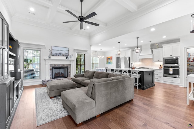 living area featuring a ceiling fan, a fireplace, coffered ceiling, dark wood-style floors, and beam ceiling