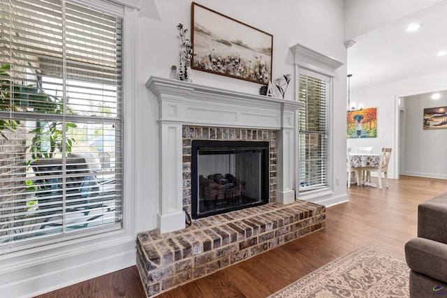 living area featuring wood finished floors, baseboards, a brick fireplace, and recessed lighting