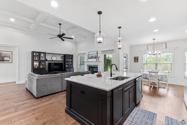 kitchen featuring a sink, recessed lighting, a glass covered fireplace, wood finished floors, and stainless steel dishwasher