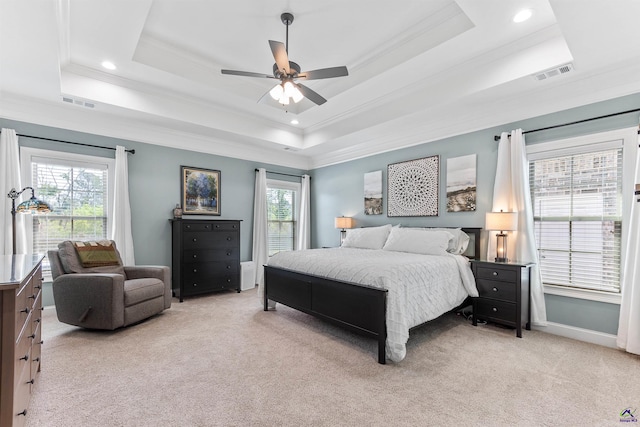bedroom featuring light colored carpet, multiple windows, a tray ceiling, crown molding, and baseboards