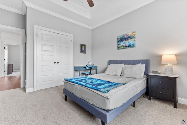 bedroom featuring light colored carpet, crown molding, a closet, baseboards, and ceiling fan
