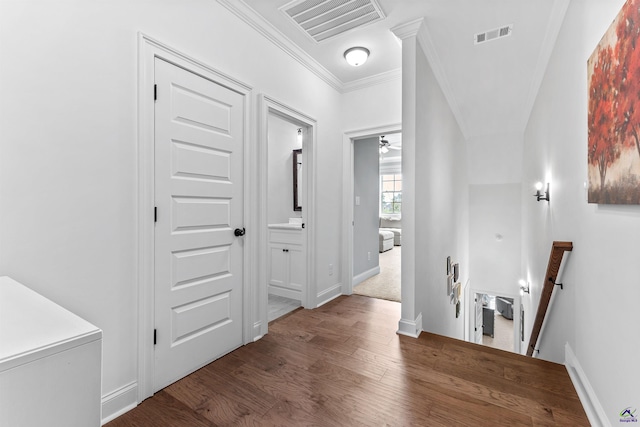corridor with an upstairs landing, crown molding, wood finished floors, and baseboards