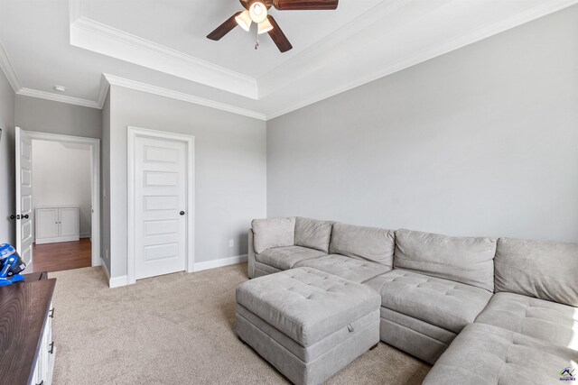 living area featuring ceiling fan, a tray ceiling, carpet flooring, crown molding, and baseboards