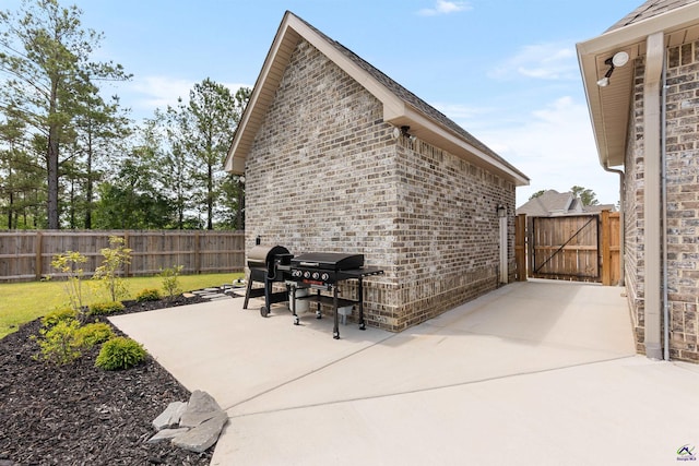 view of patio / terrace featuring fence, a grill, and a gate