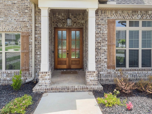 view of exterior entry featuring french doors and brick siding