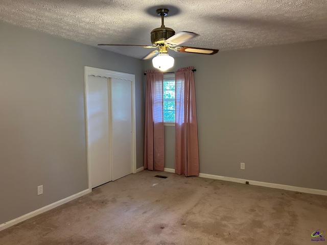 carpeted empty room featuring a ceiling fan, a textured ceiling, and baseboards