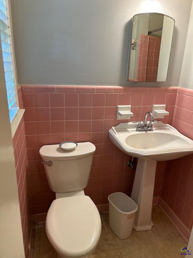 bathroom with tile walls, wainscoting, tile patterned flooring, and toilet