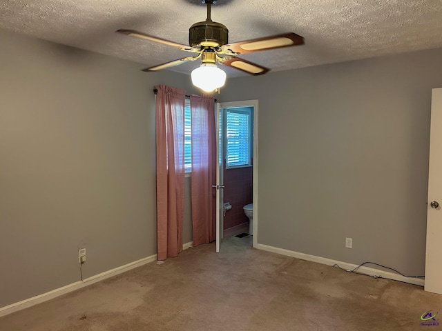 carpeted empty room featuring ceiling fan, a textured ceiling, and baseboards