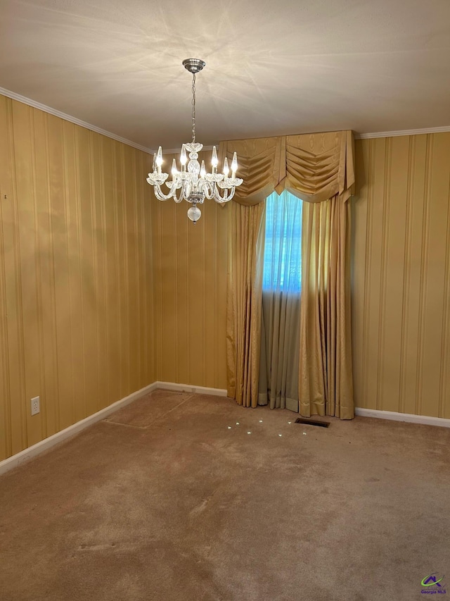 spare room with a chandelier, carpet flooring, crown molding, and baseboards