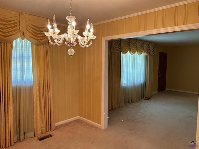 unfurnished dining area with a chandelier, crown molding, carpet floors, and baseboards