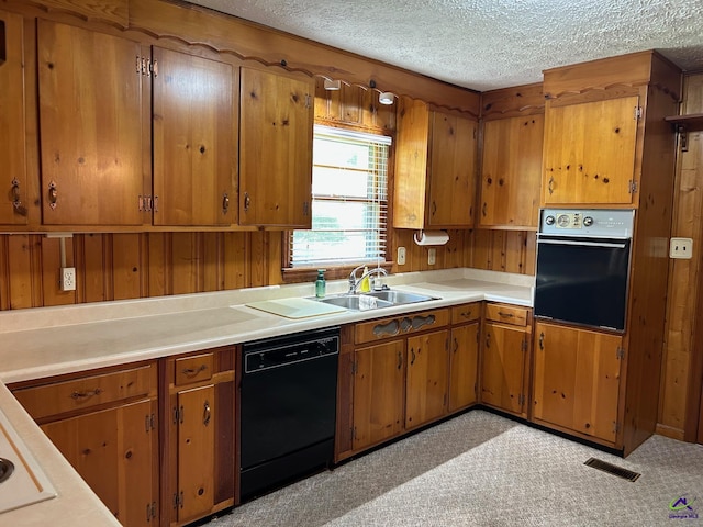 kitchen with black appliances, a sink, brown cabinetry, light countertops, and a textured ceiling