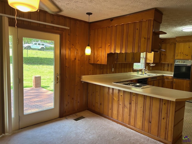 kitchen featuring oven, brown cabinets, a textured ceiling, light countertops, and a peninsula