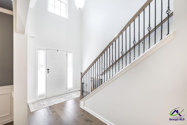 foyer entrance featuring wood finished floors, a towering ceiling, and stairs