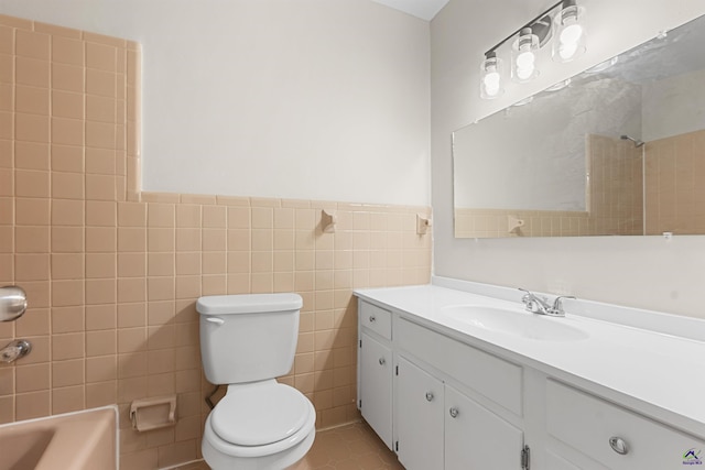 full bath with toilet, vanity, tile walls, a wainscoted wall, and tile patterned floors