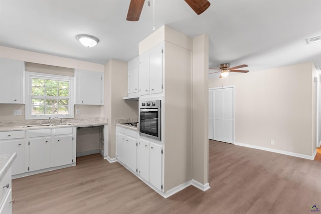 kitchen with ceiling fan, stainless steel appliances, a sink, light wood finished floors, and light countertops