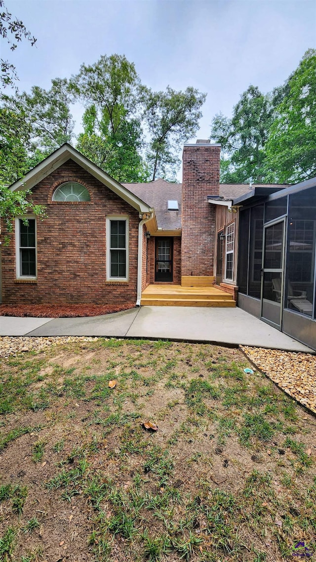213 Falcon Crst, Warner Robins, GA 31088 - back of house featuring a chimney, a sunroom, a patio, and brick siding