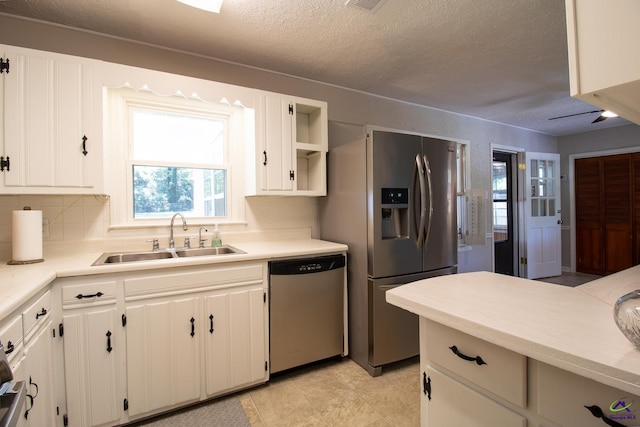 kitchen with stainless steel appliances, a sink, decorative backsplash, a textured ceiling, and light countertops