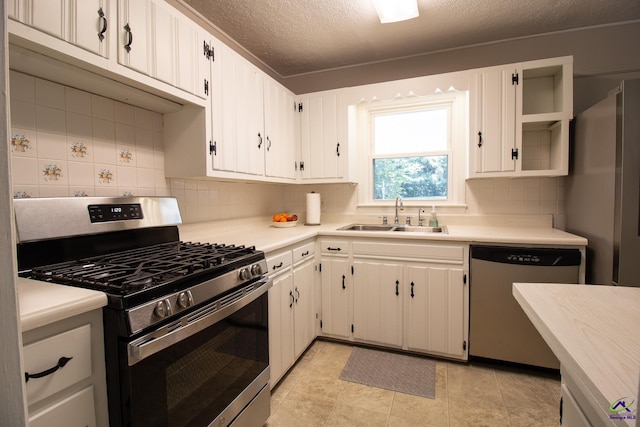 kitchen featuring appliances with stainless steel finishes, a sink, light countertops, a textured ceiling, and backsplash