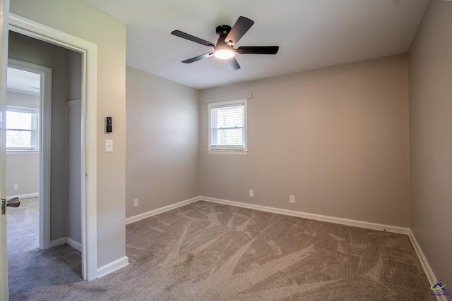 carpeted spare room featuring a ceiling fan and baseboards