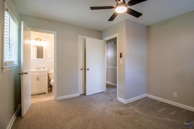 unfurnished bedroom featuring light carpet, a sink, connected bathroom, and baseboards