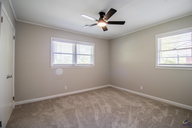 empty room with light colored carpet, a ceiling fan, baseboards, and crown molding