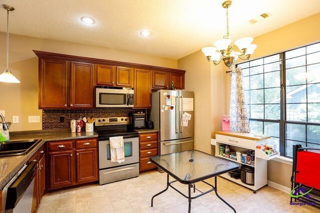 209 Ridgestone, Warner Robins, GA 31088 - kitchen featuring stainless steel appliances, a chandelier, pendant lighting, backsplash, and dark countertops