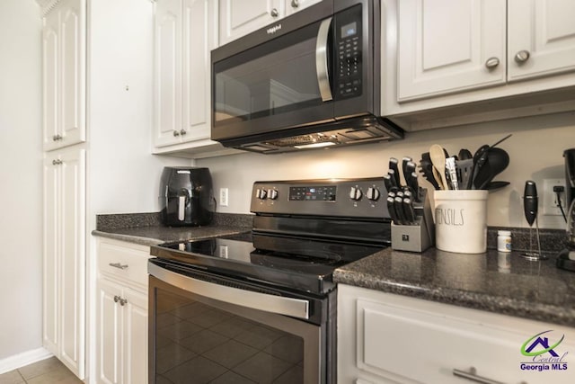 kitchen featuring stainless steel range with electric stovetop, white cabinetry, and light tile patterned floors