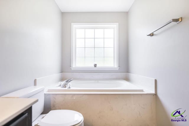 bathroom with toilet, a garden tub, and vanity