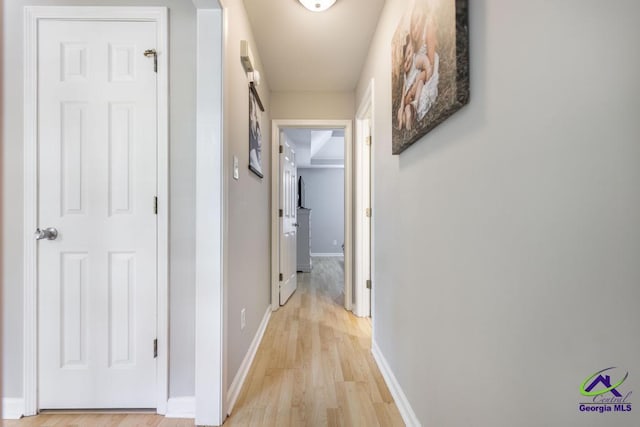 corridor featuring light wood-style floors and baseboards