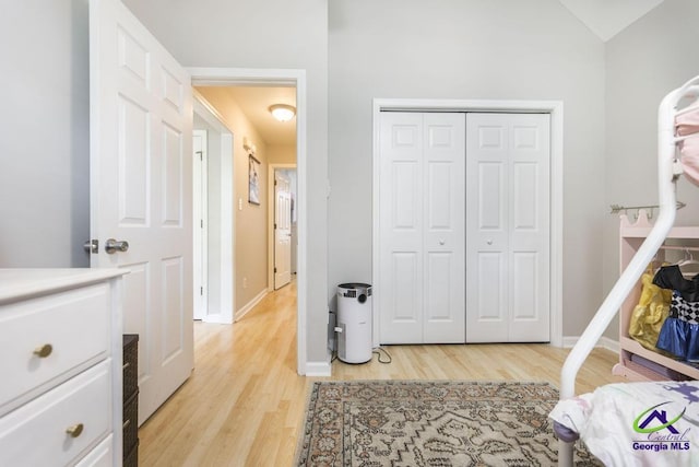 bedroom with light wood-style floors, baseboards, and a closet