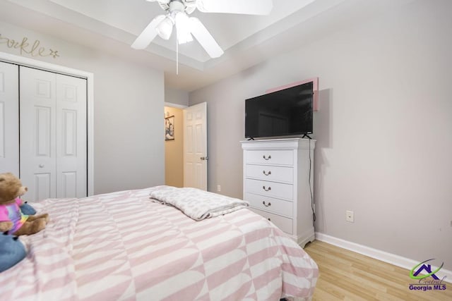 bedroom with light wood-style flooring, a closet, baseboards, and ceiling fan