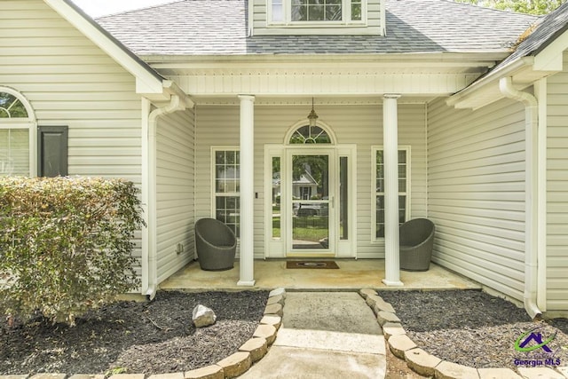 entrance to property featuring a shingled roof and a porch