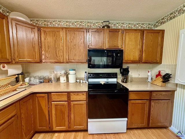kitchen featuring black appliances, brown cabinetry, light wood-style flooring, light countertops, and a textured ceiling