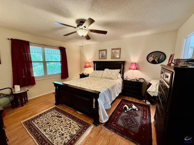 bedroom featuring multiple windows, wood finished floors, a textured ceiling, and a ceiling fan