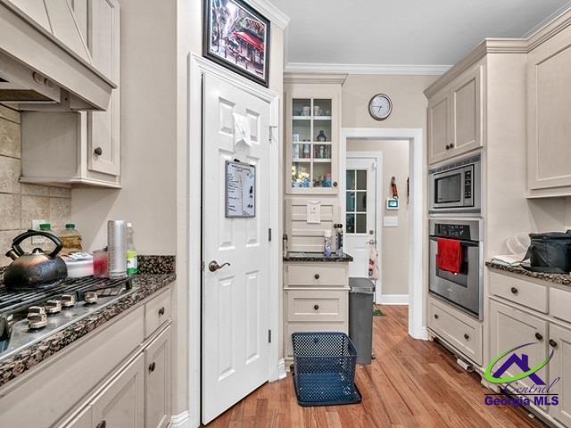 163 Broadleaf Dr, Macon, GA 31210 - kitchen with appliances with stainless steel finishes, light wood finished floors, backsplash, dark stone counters, and ornamental molding