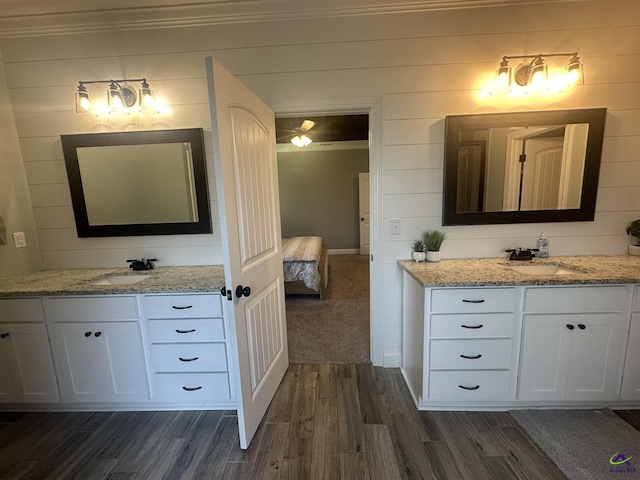 ensuite bathroom featuring wood finished floors, crown molding, and two vanities