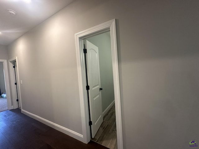hallway featuring dark wood finished floors and baseboards