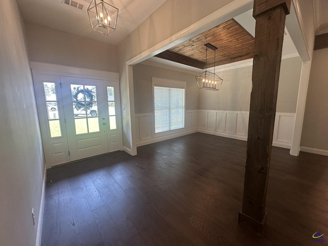 entryway with a chandelier, dark wood-style floors, a wainscoted wall, a decorative wall, and ornamental molding
