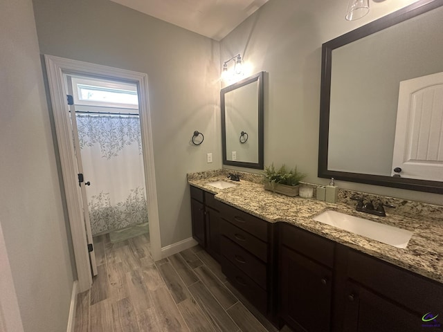 bathroom featuring wood finished floors, double vanity, baseboards, and curtained shower