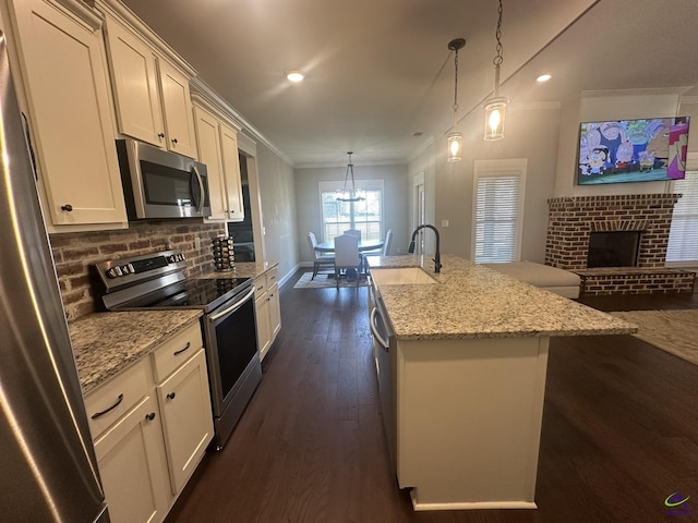 kitchen with stainless steel appliances, a sink, ornamental molding, dark wood-style flooring, and a center island with sink