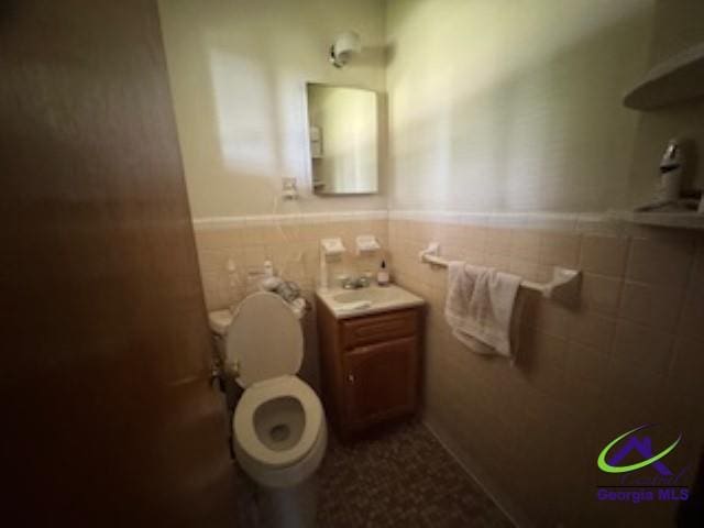 111 Mason Dr, Centerville, GA 31028 - half bathroom featuring tile walls, a wainscoted wall, toilet, and a sink
