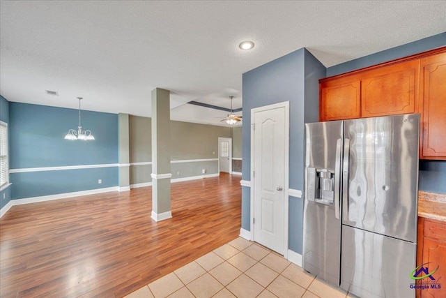 kitchen with stainless steel fridge with ice dispenser, brown cabinets, a chandelier, light wood-style floors, and a textured ceiling