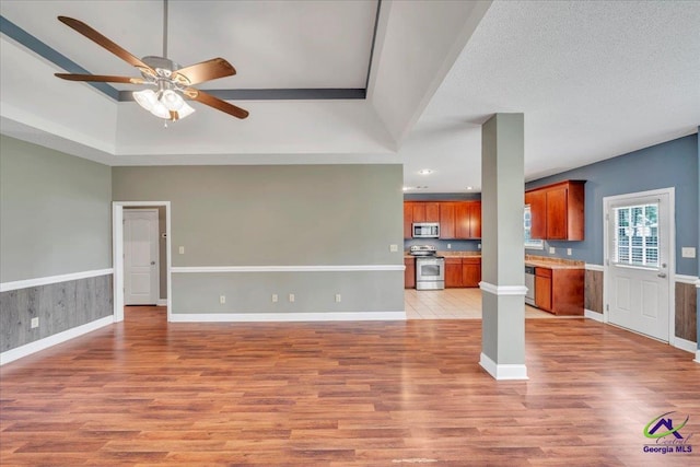 unfurnished living room with ceiling fan, light wood finished floors, a raised ceiling, recessed lighting, and baseboards