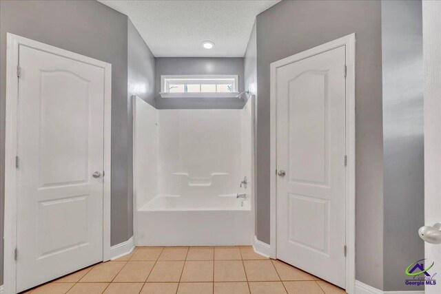 full bath with baseboards, tile patterned floors, bathtub / shower combination, and a textured ceiling