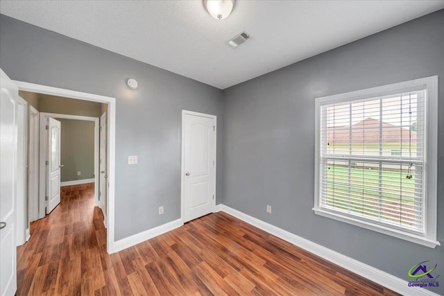 unfurnished bedroom with wood finished floors, baseboards, and a closet