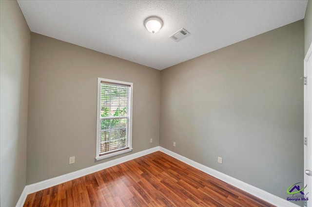 empty room with dark wood-style floors, baseboards, and a textured ceiling