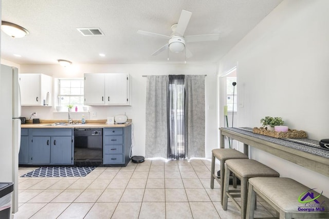kitchen featuring black dishwasher, a sink, a ceiling fan, white cabinets, and light countertops