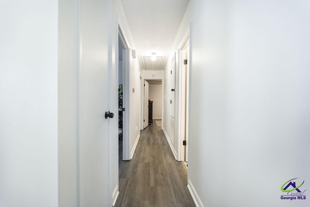 corridor with attic access, dark wood finished floors, and baseboards