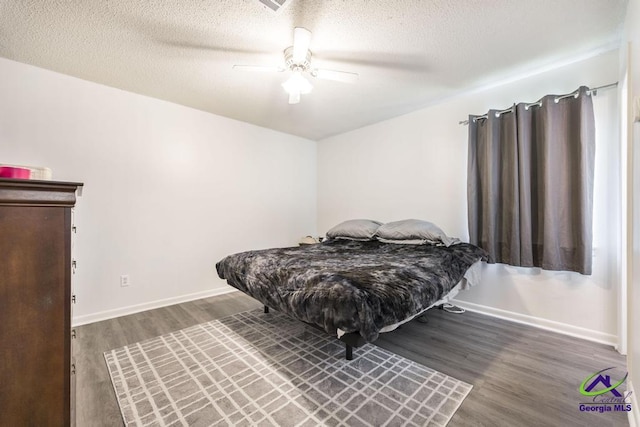 bedroom with wood finished floors, a textured ceiling, baseboards, and a ceiling fan